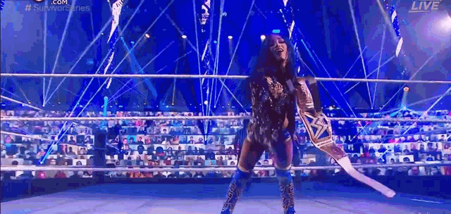 a woman is standing in a wrestling ring holding a sword and a championship belt .