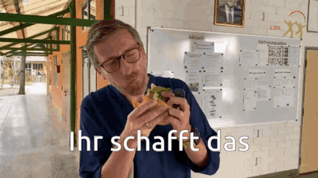 a man eating a sandwich with the words ihr schafft das written below him