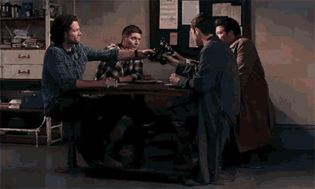 four men are sitting around a table drinking beer .