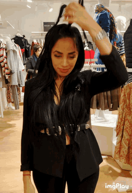 a woman in a black jacket is standing in a store with a sign that says ' imgplay ' on it