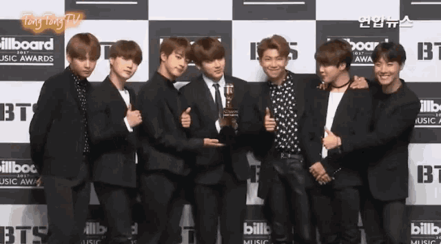 a group of men standing in front of a wall that says billboard