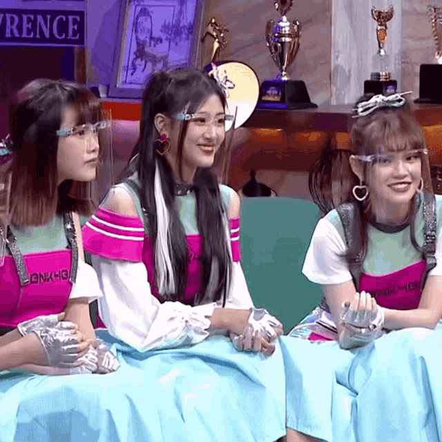 three girls are sitting in front of a sign which says rence