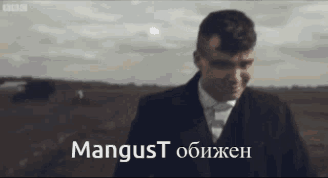 a man in a suit and tie is standing in a field with the words mangust written in white letters