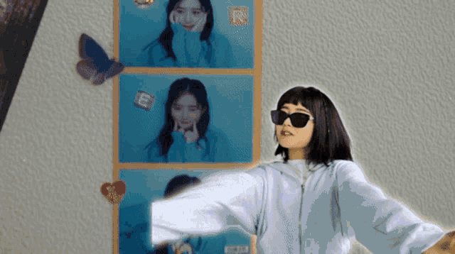 a woman wearing sunglasses is standing in front of a wall with pictures of a woman and the letter e on it