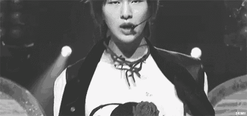 a black and white photo of a young man singing into a microphone .