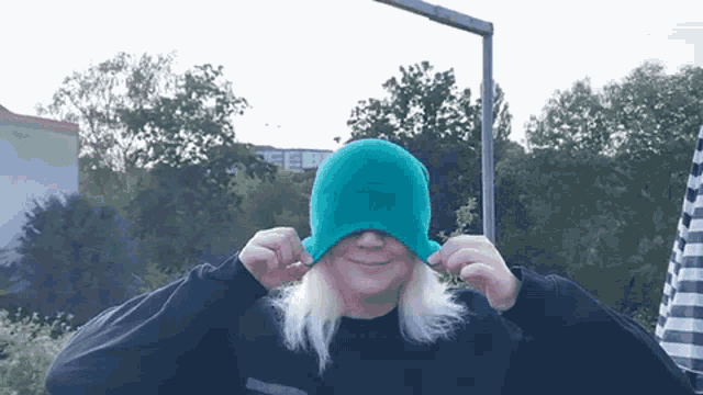 a woman wearing a black sweater and a green hat