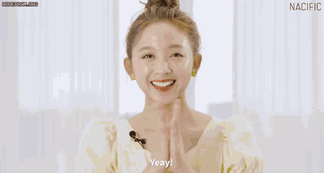 a woman wearing a yellow shirt is clapping her hands and says yeay