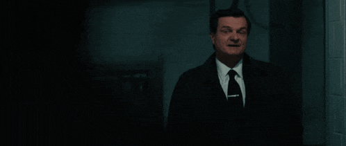 a man in a suit and tie is standing in the dark