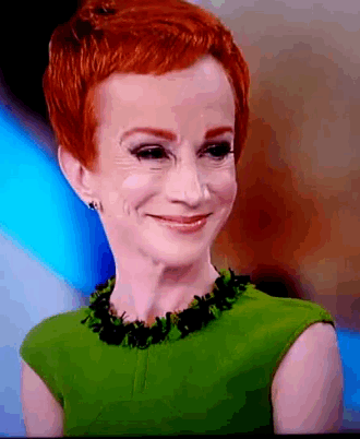 a woman with red hair is wearing a green top and black necklace