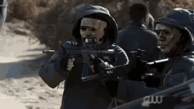 a group of people wearing masks and holding guns in a field .
