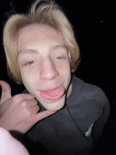 a young man sticking his tongue out while wearing a black columbia sweatshirt