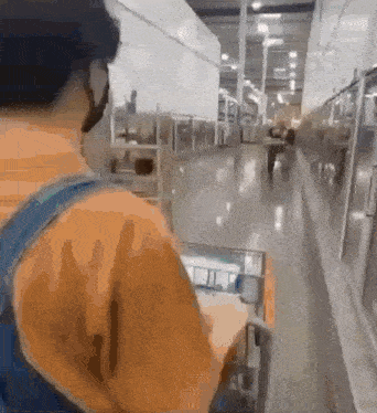a man wearing a mask is walking down a hallway in a warehouse