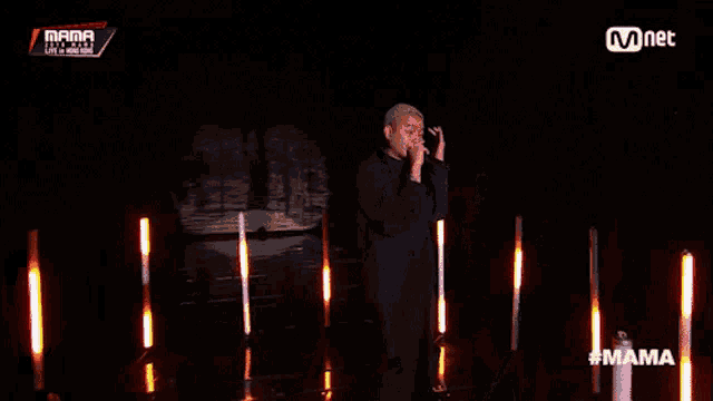 a man singing into a microphone on a stage with a mnet logo behind him