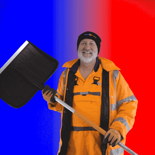 a man wearing an orange jacket and a black hat holds a large black snow shovel