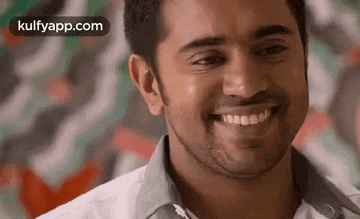 a close up of a man 's face smiling in front of a wall .