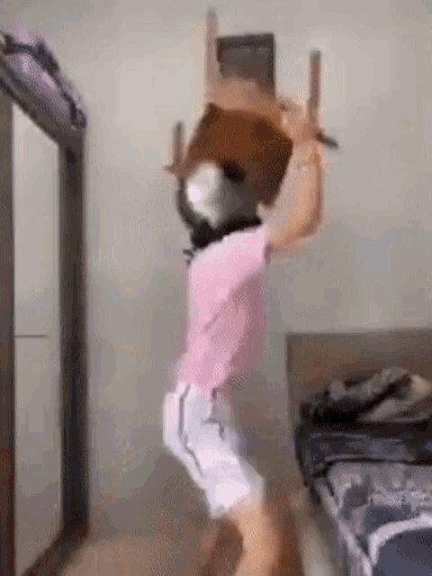 a person is holding a chair on their head in a room .