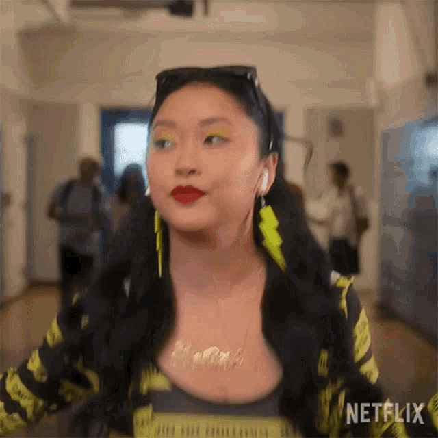 a woman wearing a necklace and earrings is standing in a hallway with a blurred background .