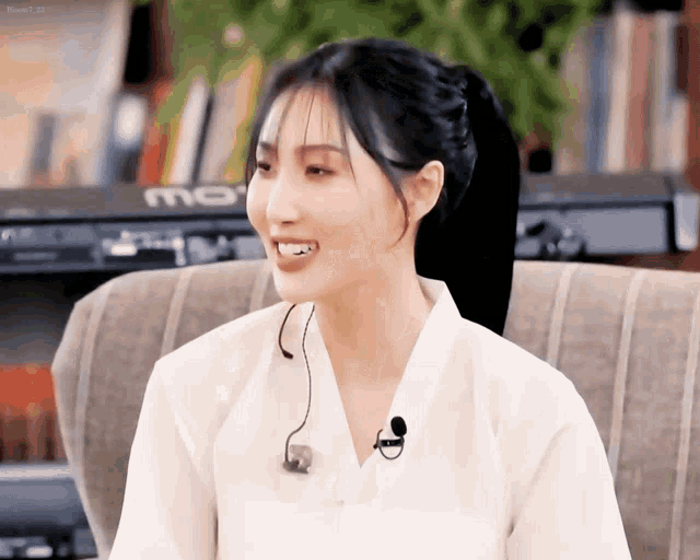 a woman wearing a white shirt with a microphone around her neck smiles