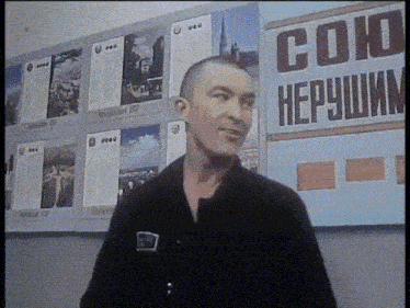 a man stands in front of a wall with a sign that says " союз "
