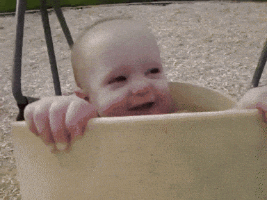 a baby is sitting on a swing in a playground