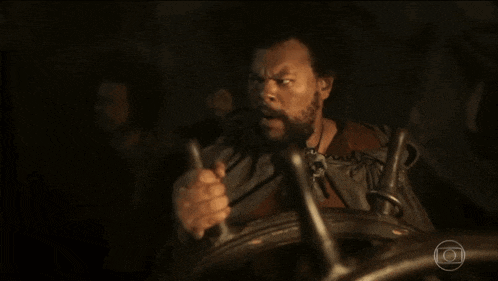 a man with a beard is holding a steering wheel in his hand