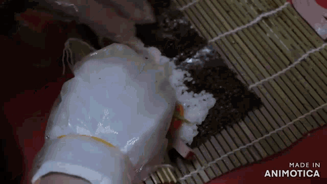 a person is making sushi on a bamboo mat with the words made in animotica on the bottom
