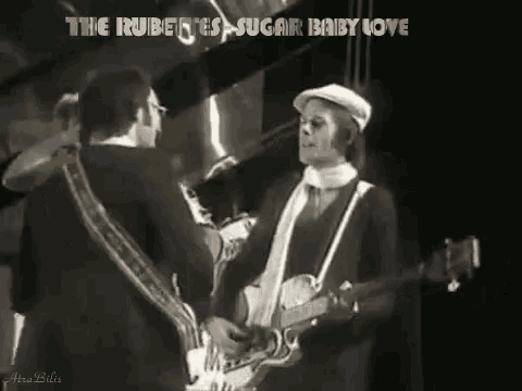 a man playing a guitar and another man playing a saxophone with the words " the rubettes sugar baby love " above