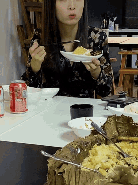 a woman sits at a table with a can of coca cola