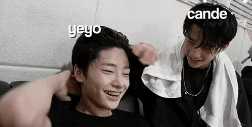 two young men are sitting next to each other on a couch and laughing .