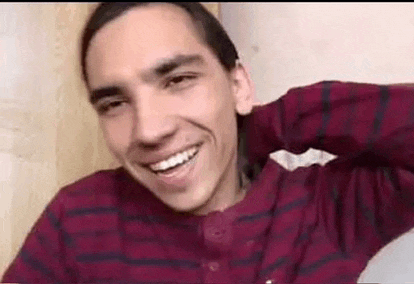 a young man wearing a red and black plaid shirt is smiling .