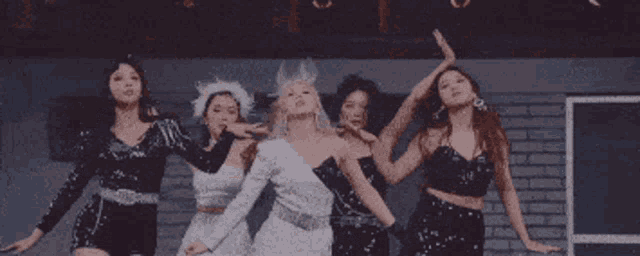 a group of women are dancing together in a dark room
