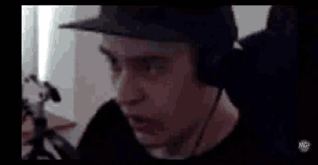 a man wearing headphones and a hat is sitting in a chair .