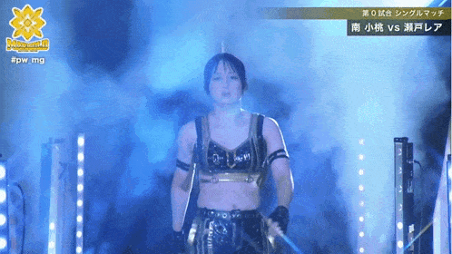 a female wrestler stands in a dark room with a sign that says #pwmg