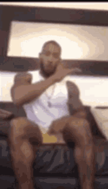 a man is sitting on a couch with his legs crossed and talking on a phone .