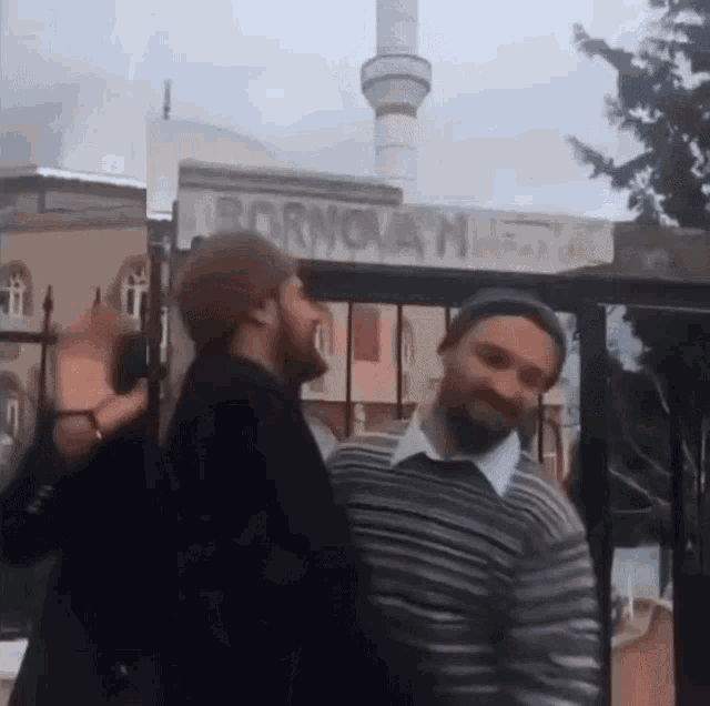 two men are standing in front of a sign that says bornoan mosque