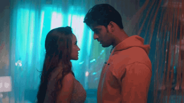 a man and a woman are looking at each other in a room