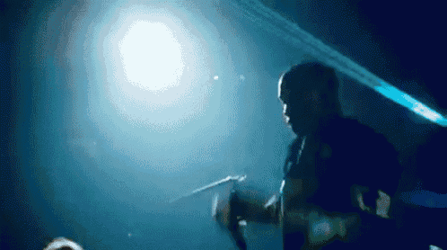 a man holding a microphone in a dark room with a blue light behind him