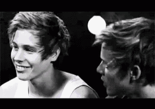 a black and white photo of two young men looking at each other .