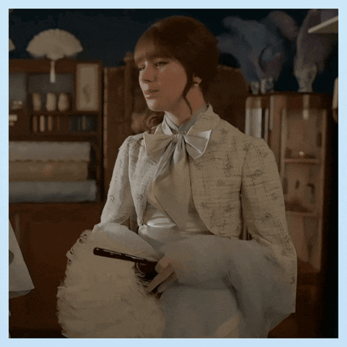 a woman in a white jacket holds a white fan