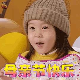 a little girl wearing a knitted hat and a bib says happy mother 's day in chinese
