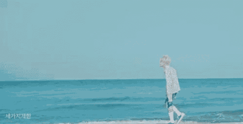 a man is walking along the beach near the ocean .