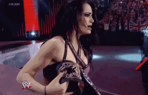 a woman is holding a wrestling championship belt in her hand on a stage .
