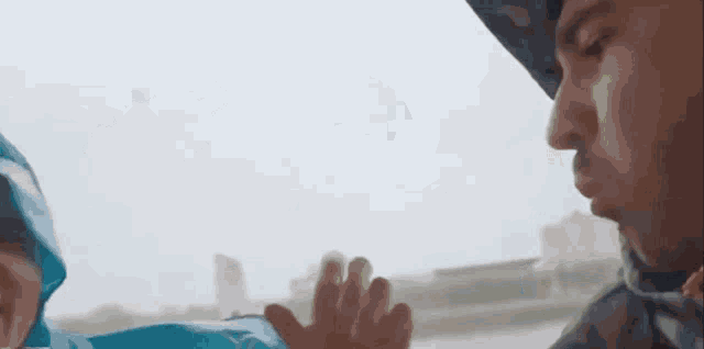 a man in a blue raincoat holds a bottle in his hand
