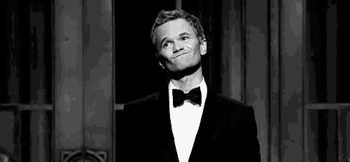 a man in a tuxedo and bow tie is making a face .