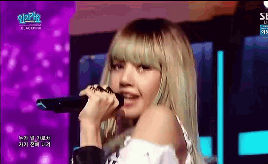 a woman with blonde hair is singing into a microphone on stage .