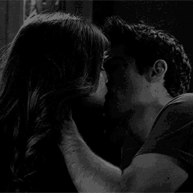 a man and a woman kissing in a black and white photo .