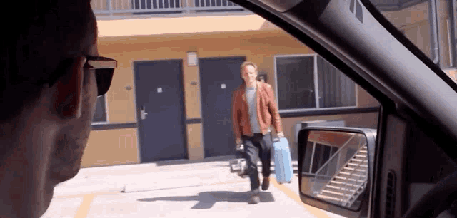 a man carrying a suitcase is walking towards a building