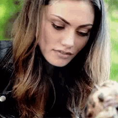 a woman in a black jacket is looking at a squirrel .