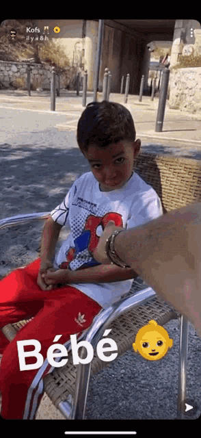 a young boy wearing a spiderman shirt is sitting in a chair being held by a man .