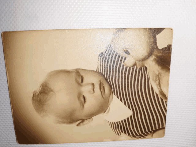 a black and white photo of a baby wearing a striped outfit